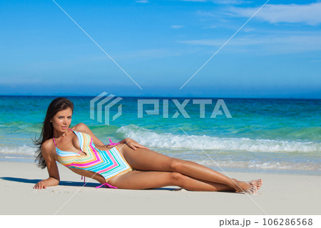 Woman in swimwear laying by sea 106286568