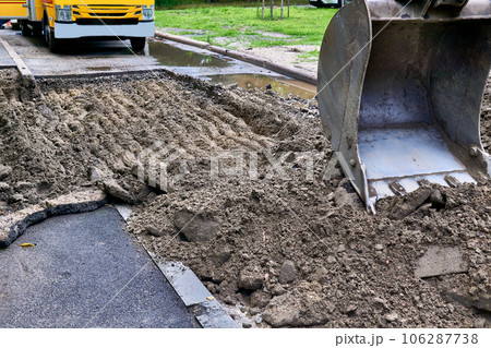 Excavator bucket picking up the ground, soil on road repair 106287738