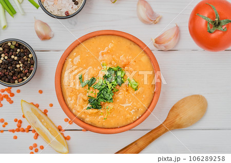 Red lentil soup with ingredients on a wooden white plate, top view. Traditional Turkish or Arabic Lentil Vegetable Spicy Soup. Healthy Middle Eastern Vegan Food 106289258