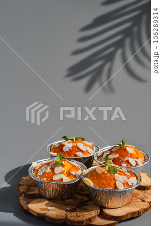 Delicious lemon muffins or cupcakes with frosting and almond flakes. Homemade magdalena on gray neutral background, dish serving idea, close-up, selective focus 106289314