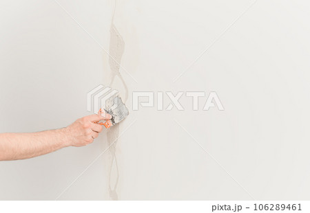 Putty knife with putty in hand, worker puts plaster on the wall. Selective focus. The concept of renovation work in apartments or offices, construction. Free space for ad or text 106289461