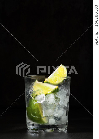 Glass of lime lemonade on a dark table, summertime drinks. Homemade lemonade with lime and ice cube. Idea cold fresh drinks 106290163