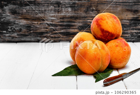 Juicy fruits peaches with leaves on wooden background, copy space Juicy fruits peaches with leaves on wooden background, copy space 106290365