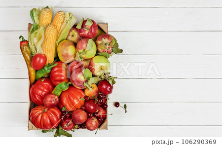 Fresh and colorful vegetables and fruits in a box on a white wooden table with copy space. Fresh food delivery from the store, seasonal vegetables. 106290369