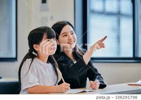 ホワイトボードを見つめる小学生の女の子と若い塾講師 106291796