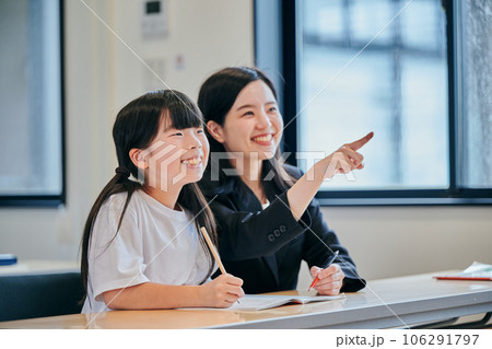 ホワイトボードを見つめる小学生の女の子と若い塾講師 106291797