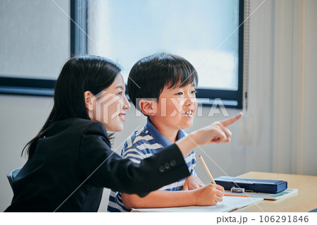 ホワイトボードを見つめる小学生の男の子と若い塾講師 ホワイトボードを見つめる小学生の男の子と若い塾講師 106291846