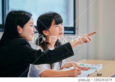 ホワイトボードを見つめる小学生の女の子と若い塾講師 106291874