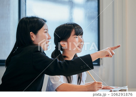 ホワイトボードを見つめる小学生の女の子と若い塾講師 106291876