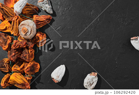 Dried persimmon on a black table. Top view of sweet dried persimmon. Traditional Japanese dessert cuisine. Naturally sun-dried persimmons Dried persimmon on a black table. Top view of sweet dried persimmon. Traditional Japanese dessert cuisine. Naturally sun-dried persimmons 106292420
