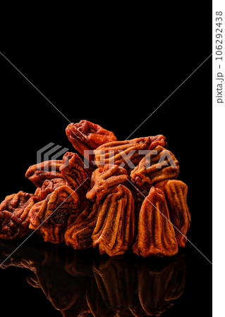 Sun-dried persimmons on a black mirror table, close-up, selective focus on fruits. Vertical frame. Traditional Japanese dessert of dried persimmon Sun-dried persimmons on a black mirror table, close-up, selective focus on fruits. Vertical frame. Traditional Japanese dessert of dried persimmon 106292438