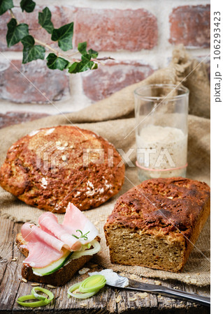 Sandwich with onions and ham on a slice of fresh bread. Sourdough rye yeast bread, cut into slices on a rustic wooden background. Healthy natural food. 106293423