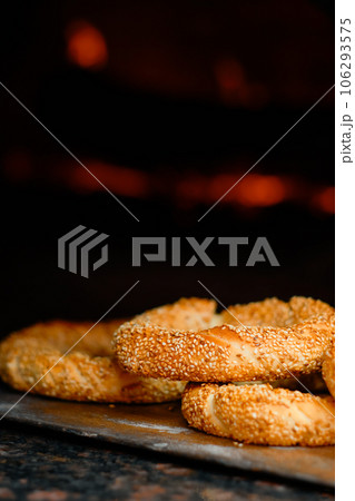 Freshly baked simit baked goods with sesame seeds close-up (Turkish bagel - Gevrek or Kuluri) in front of the hearth. Traditional white bread with sesame seeds for breakfast, close up 106293575