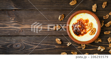 Turkish Cuisine dessert varieties. Baked rice pudding - turkish milk dessert sutlac in earthenware casserole with walnuts. Top view with copy space 106293579