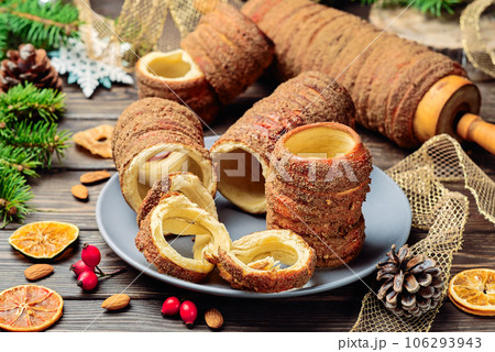 Trdelnik is a baked delicacy on a spit and charcoal dough with sugar, cinnamon and vanilla. Christmas sweets, street food. Czech and Moravian cuisine. Trdelnik is a baked delicacy on a spit and charcoal dough with sugar, cinnamon and vanilla. Christmas sweets, street food. Czech and Moravian cuisine. 106293943