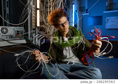 Confused IT networking engineer looking with disbelief on ethernet cables 106295563