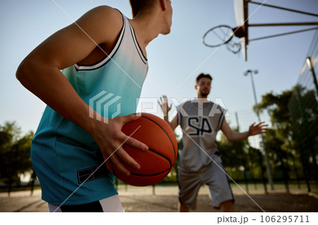 Closeup teenager son preparing to throw ball into basket hoop Closeup teenager son preparing to throw ball into basket hoop 106295711