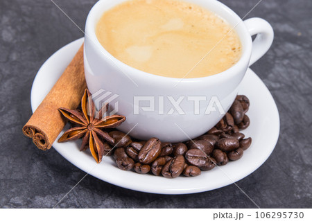 Coffee in white cup and roasted dark coffee beans with seasonings Coffee in white cup and roasted dark coffee beans with seasonings 106295730