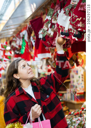 Portrait of girl with paper bags choosing Christmas tree balls at street fair 106297118