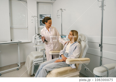 Nurse or doctor talking with patient while preparing her for infusion drip in hospital Nurse or doctor talking with patient while preparing her for infusion drip in hospital 106300875