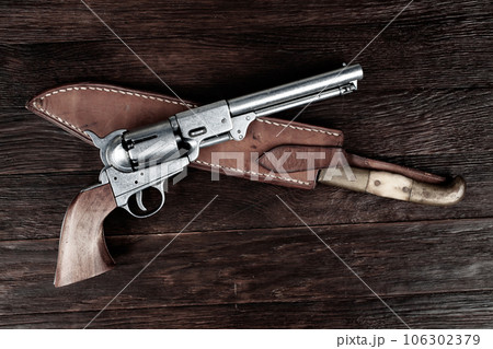 Old west weapon. Colt Revolver and knife with holster on deck. 106302379