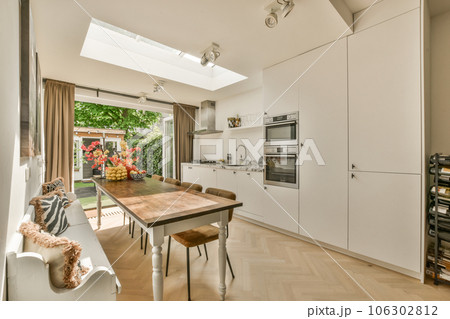 a kitchen and dining area in a house with wood flooring, white cabinets and an oven on the wall 106302812