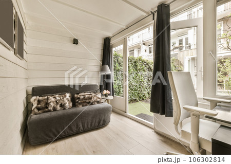 a living room with wood flooring and white walls, an open window to the garden is visible on the right side 106302814