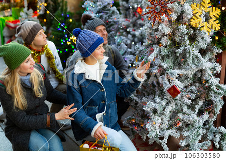 Family with two teenagers choose christmas tree at street fair Family with two teenagers choose christmas tree at street fair 106303580