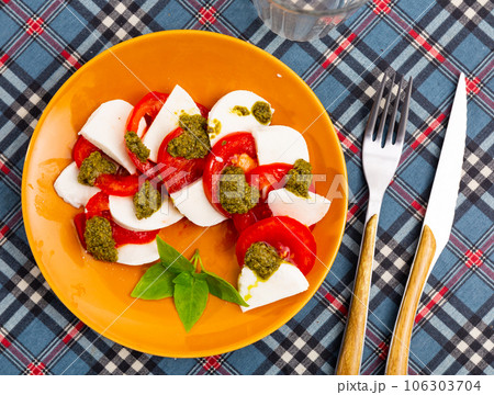Traditional snack of Italian cuisine is Caprese with basil and Pesto sauce 106303704