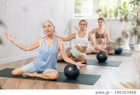 Family of three generations doing soft ball pilates exercises during group pilates class in studio 106303966