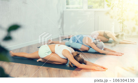 Young woman relaxing and stretching in sleeping pigeon pose in yoga studio 106304130