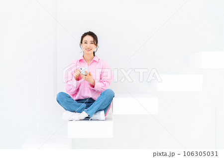 階段でスマホを見る若い女性 106305031