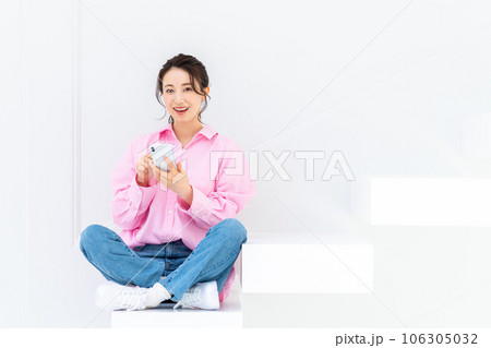 階段でスマホを見る若い女性 106305032