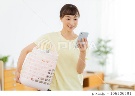 女性 洗濯 携帯電話 リビング 女性 洗濯 携帯電話 リビング 106306591