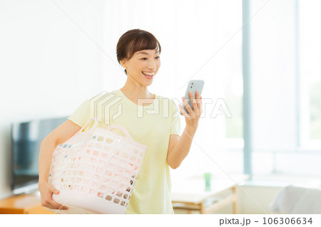 女性　洗濯　携帯電話　リビング 106306634