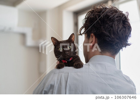 ペットの猫を抱っこする飼い主の男性の後ろ姿 106307646