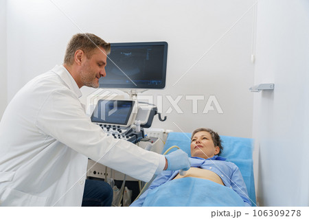 Male sonographer doing abdominal ultrasound scanning for patient in medical clinic 106309278
