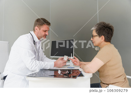 Doctor therapist prescribing pills to female patient during appointment in his office 106309279