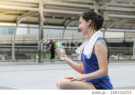 Women drinking water bottle running exercise in modern city wear wellness sportswear outside. Young woman workout outdoor exercising on bright sunny outside. Healthy wellness lifestyle woman concept Women drinking water bottle running exercise in modern city wear wellness sportswear outside. Young woman workout outdoor exercising on bright sunny outside. Healthy wellness lifestyle woman concept 106310255