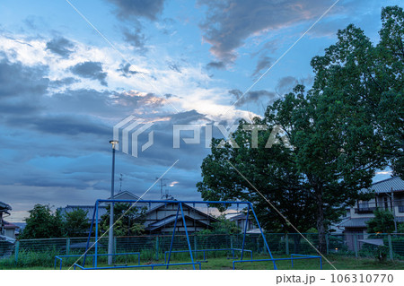 2023夏　奈良市街の公園にて　街灯のつき始めた公園で佇むブランコと雲間から見える青空 106310770