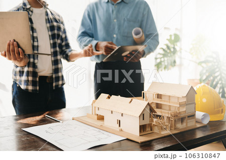 Engineer desk with object paper and tablet with blurry engineer teamwork hardworking to consults about their building project.. Engineer desk with object paper and tablet with blurry engineer teamwork hardworking to consults about their building project.. 106310847
