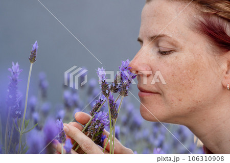 Aromatherapy, cute young womanenjoys the smell of lavender flowers while walking outdoor 106310908