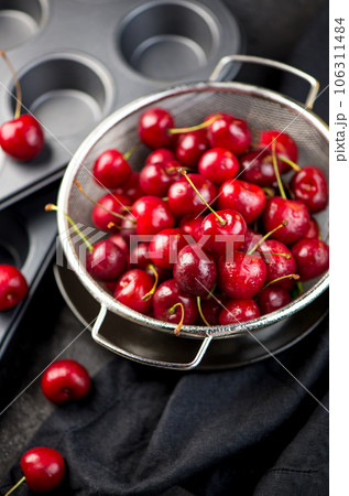 Cherry cake. Cupcakes with cherries. Cherry summer background. A large number of cherries with leaves on the table on a black background. close-up. Cherry cake. Cupcakes with cherries. Cherry summer background. A large number of cherries with leaves on the table on a black background. close-up. 106311484