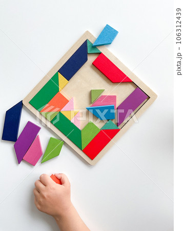 childs hand collects multicolored wooden mosaic on white background. childs hand collects multicolored wooden mosaic on white background. 106312439