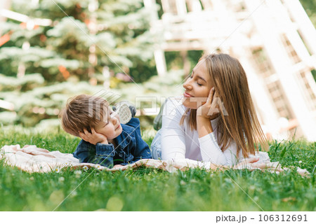 Beautiful cute young mom with her cute little son having fun lying on the grass in the park outdoors 106312691