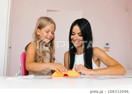 Family of a mother and a little girl smiling, playing with a toy in a game in moments of good time at home 106312696