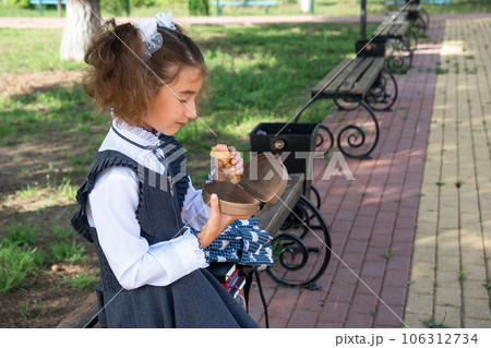 Girl with backpack eating sandwich packed in a sandwich box near school. A quick snack with a bun, unhealthy food, lunch from school. Back to school. Education, primary school classes, September 1 Girl with backpack eating sandwich packed in a sandwich box near school. A quick snack with a bun, unhealthy food, lunch from school. Back to school. Education, primary school classes, September 1 106312734