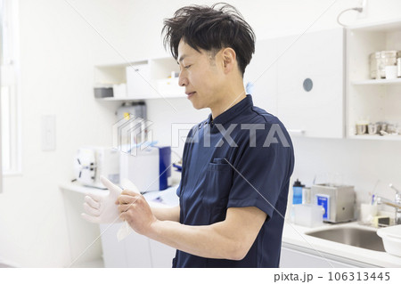 歯科治療イメージ　治療の準備で手袋をする男性歯科医 106313445