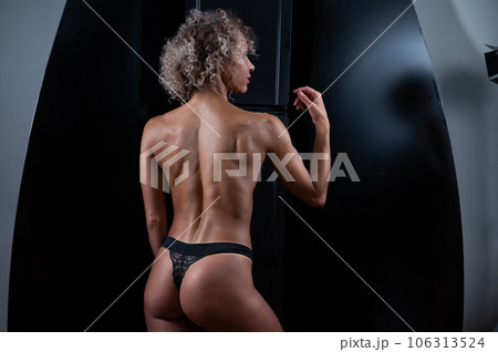 Curly blonde after the procedure of instant tanning stands with her back.  106313524