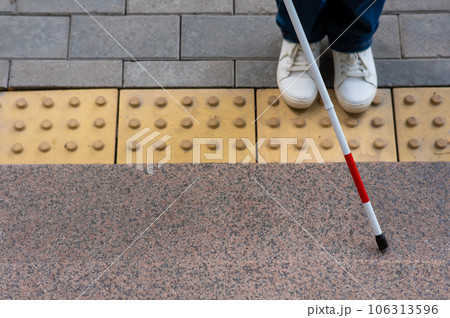 Close-up of female foot, walking stick and tactile tiles. 106313596